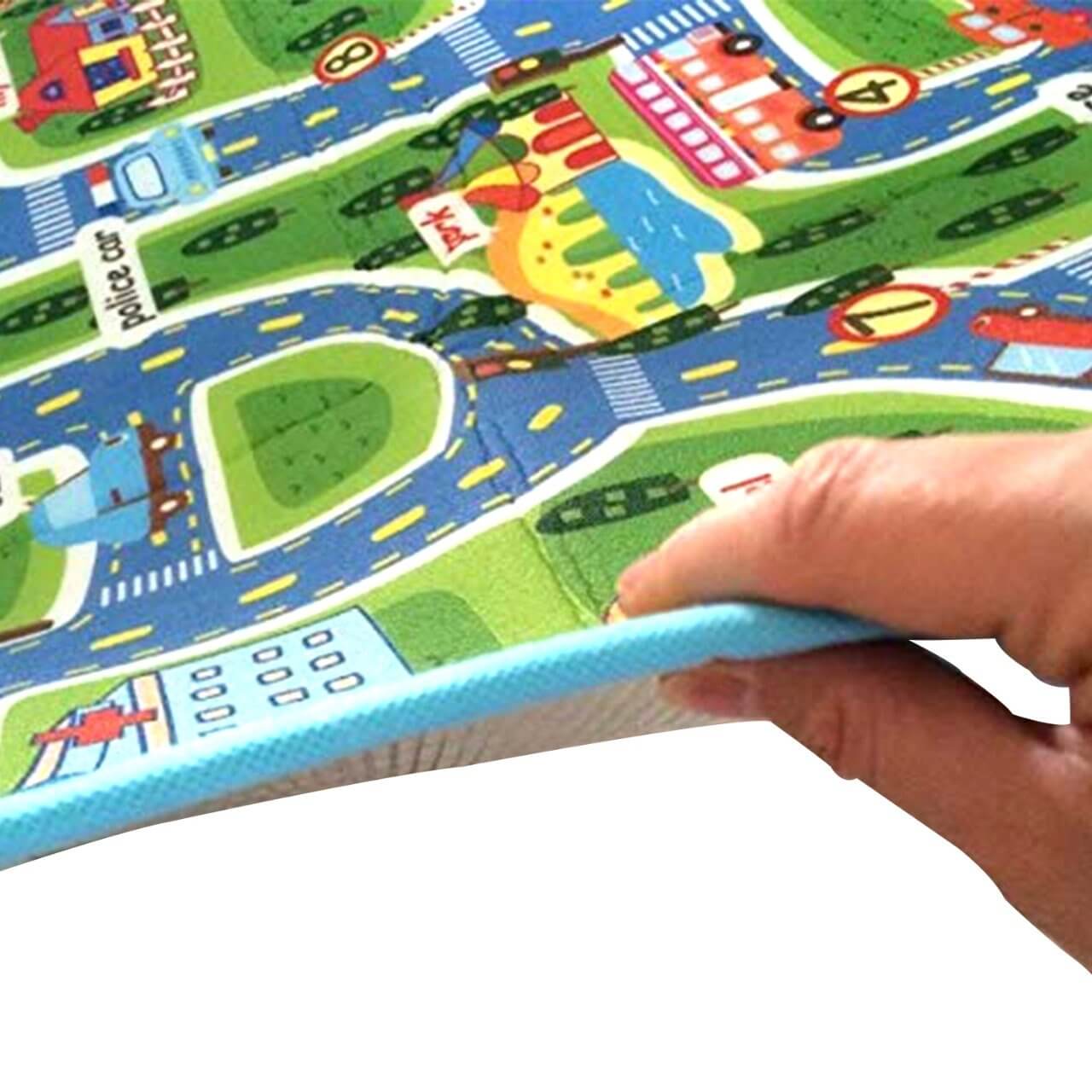 Hand holding a soft, cushioned baby play mat featuring a colorful road and city design, ideal for kids' playtime.
